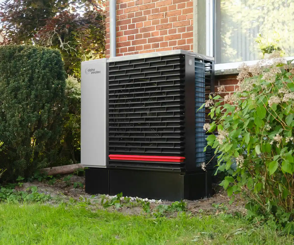 Outdoor heat pump unit installed beside a brick home