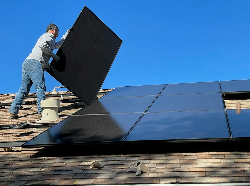 Installer placing solar panel on Edmonton rooftop